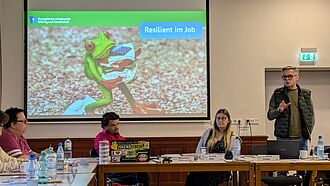 Bildschirm und Referent*innen bei einem Vortrag